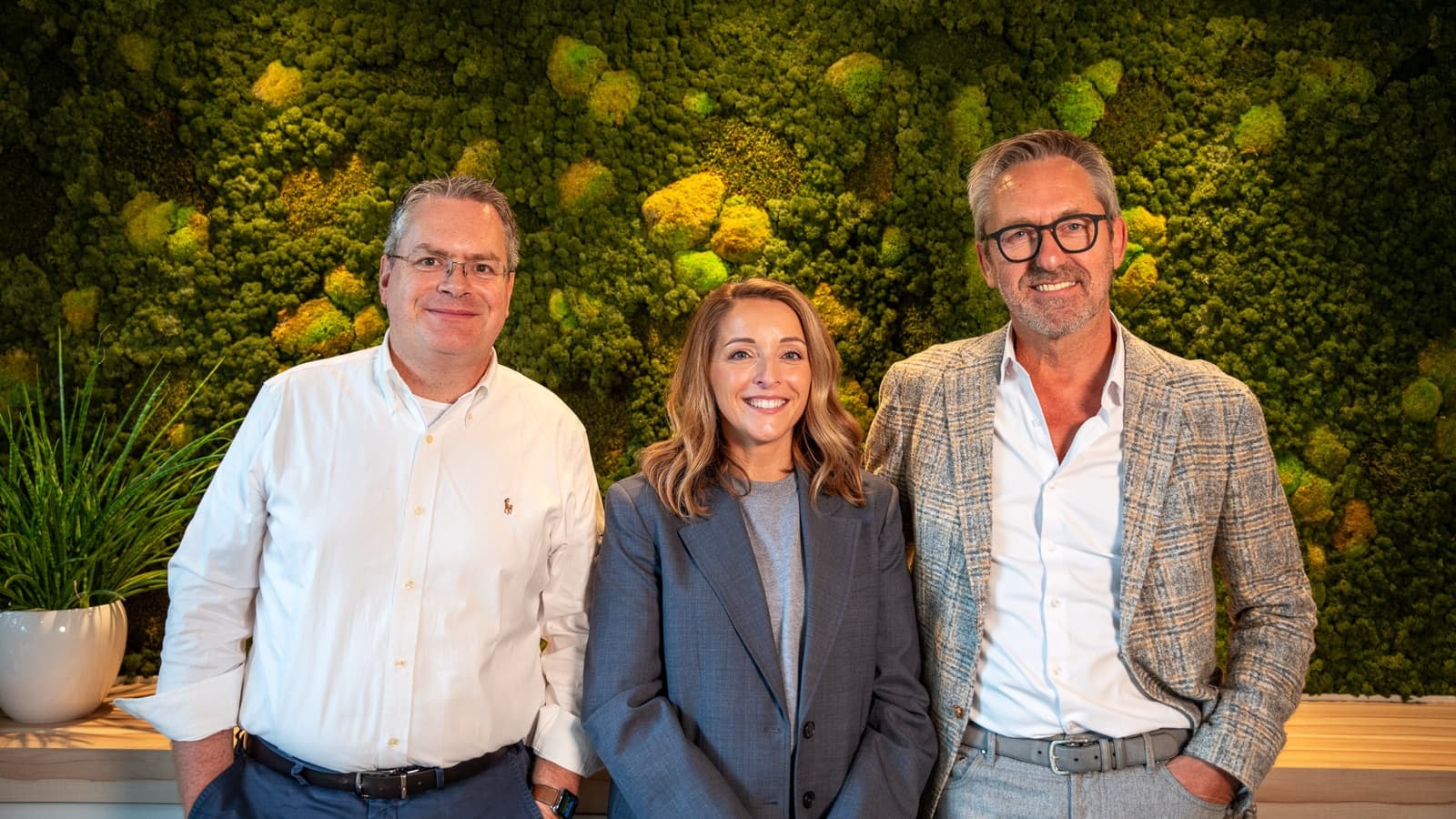 Xavier Gabriëls, Els De Ridder en Geert Motmans staan naast elkaar voor een groene mosmuur.