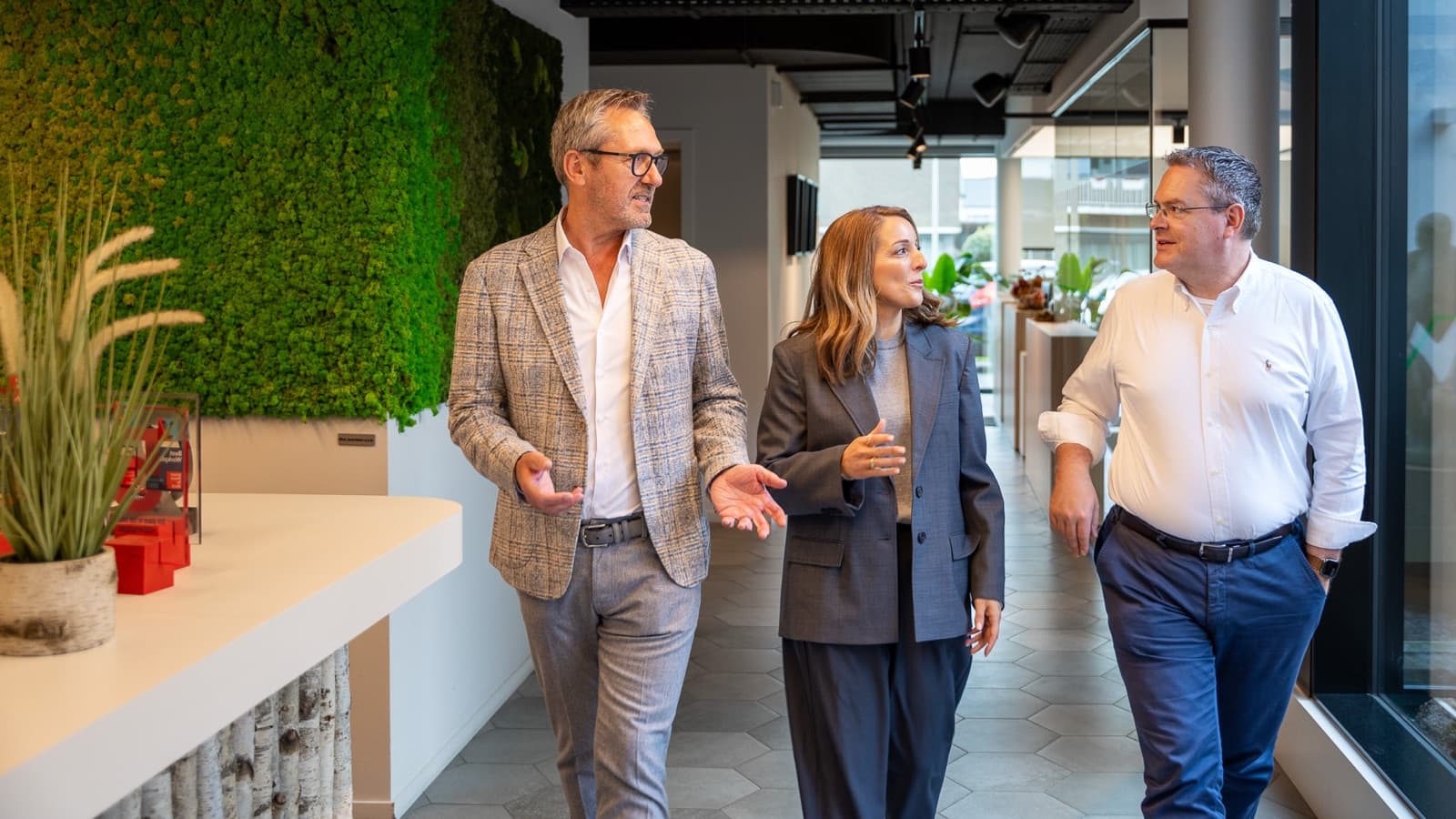 Geert, Els en Xavier lopen in gesprek door de gang