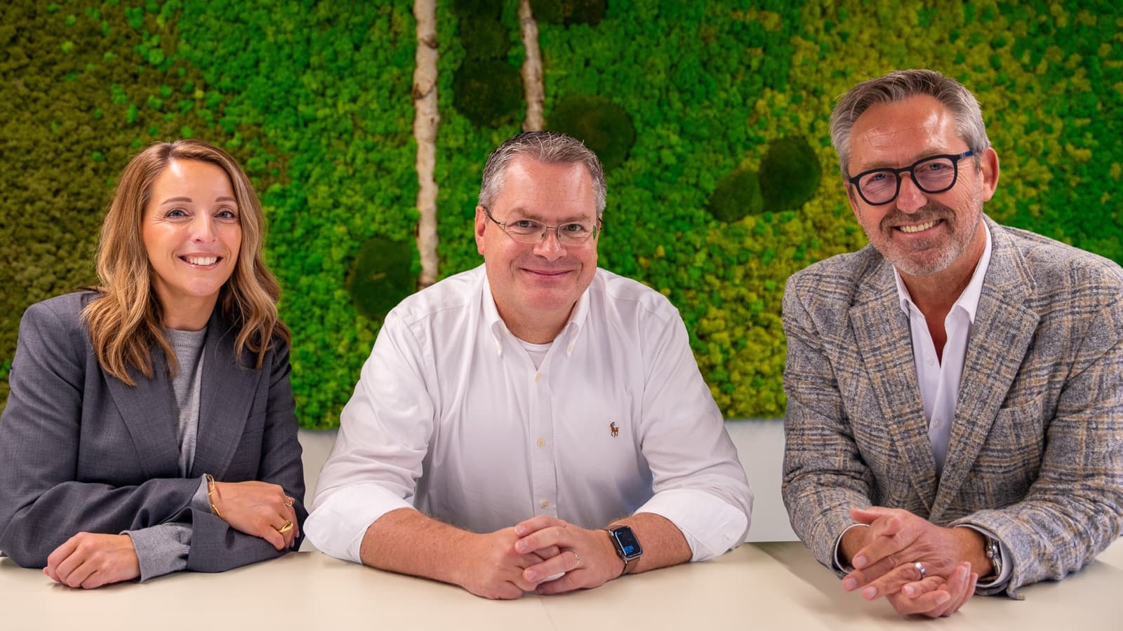Els De Ridder, Xavier Gabriëls en Geert Motmans aan tafel voor een groene mosmuur.